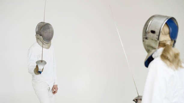 istock Two fencers having training attack and defence exercises in fencing on white background 884505864