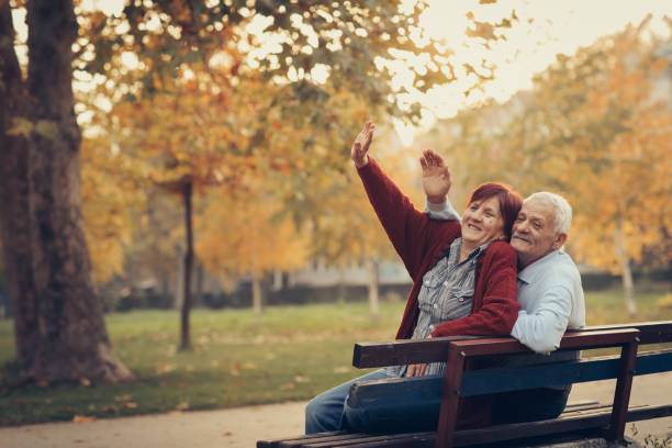 istock Happy autumn-senior couple on park bench 884506178