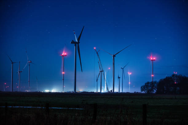 Windenergy turbines in Germany at night. Cranes are erecting new turbines. Red flash lights are blinking.