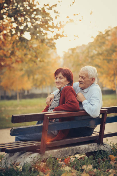 istock Happy autumn-senior couple on park bench 884521342
