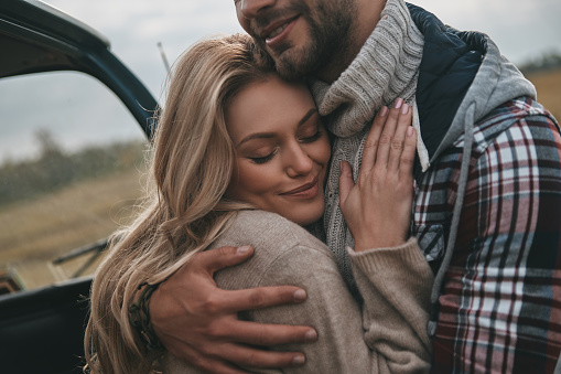 Beautiful young couple embracing and smiling while standing outdoors