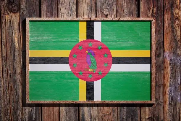 3d rendering of Dominica flag on a wooden frame over a planks wall