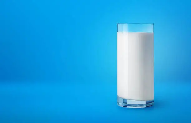 Photo of Glass of milk on blue background