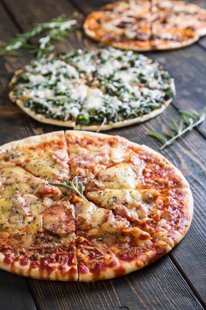 istock Varied pizzas on a wooden table 884557032