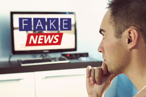 Truth misrepresented in the news on a modern TV. A fake news report. Zombie TV. Deception of viewers. Corrupt journalism. False sites. Agitation and propaganda on the screen. in front of the TV.