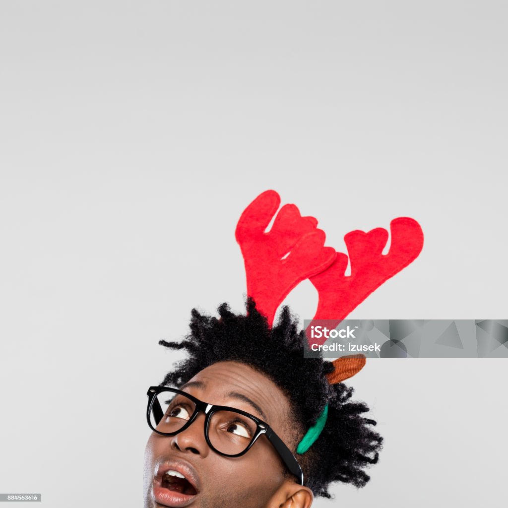 Christmas portrait of surprised nerdy man wearing reindeer handband hores, close up of face Funny christmas portrait of surprised nerdy young man wearing reindeer handband hores. Close up of face. Christmas Stock Photo