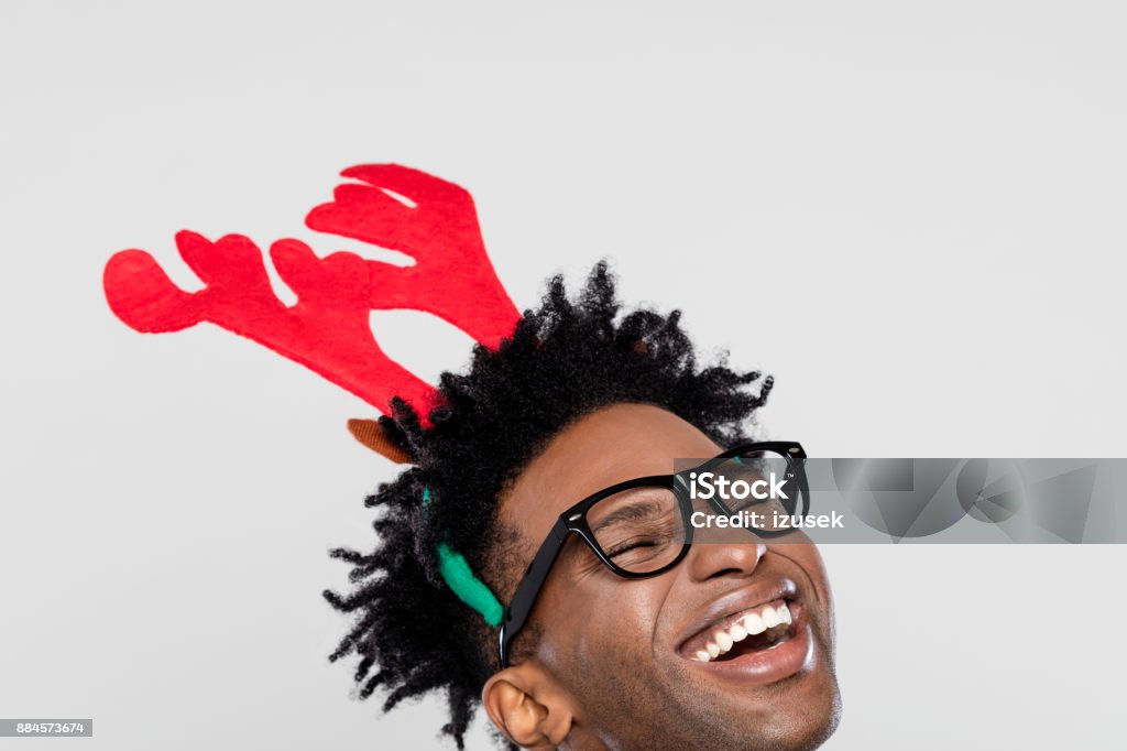 Christmas portrait of happy nerdy man wearing reindeer handband hores Funny christmas portrait of happy nerdy young man wearing reindeer handband hores. Close up of face. Christmas Stock Photo