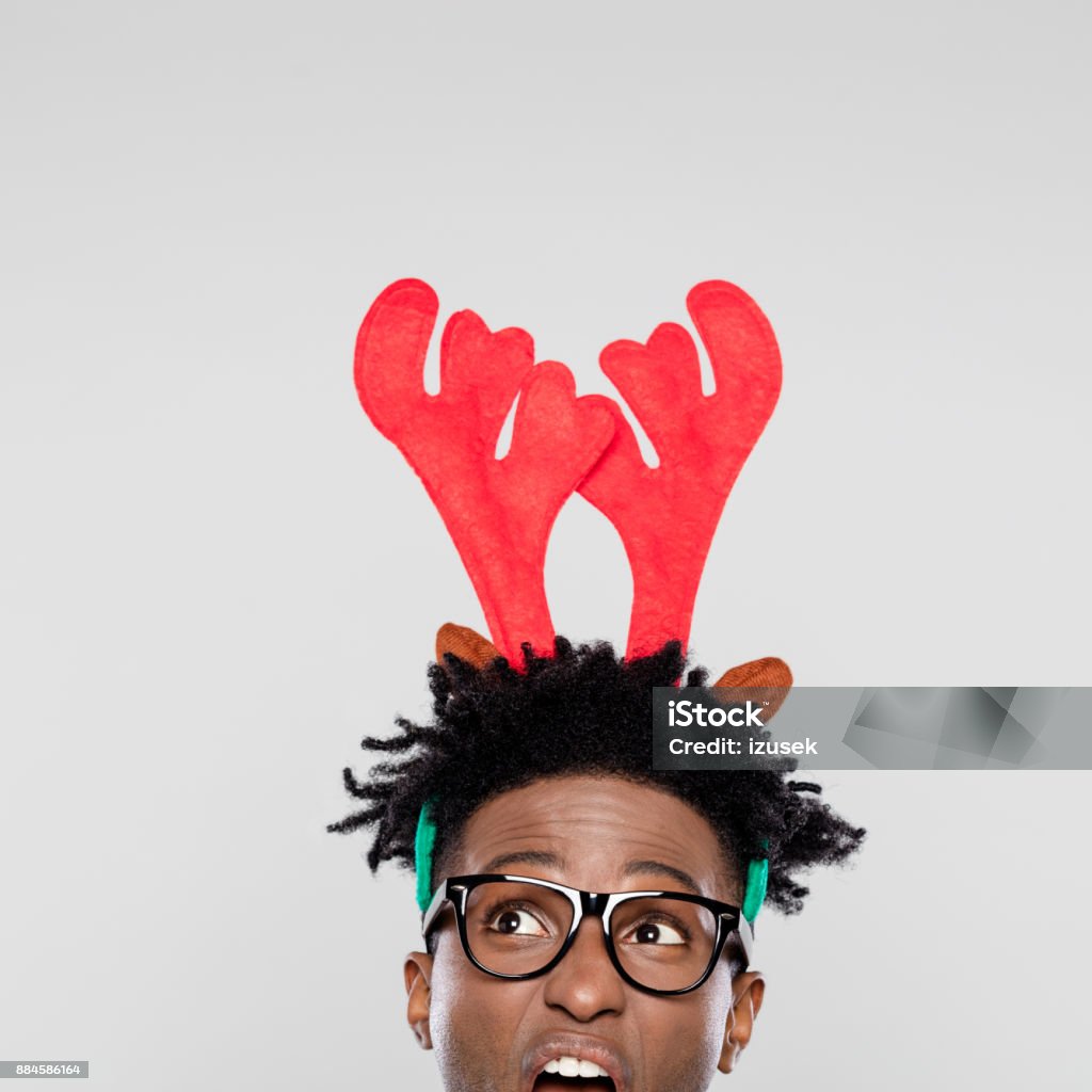 Christmas portrait of angry nerdy man wearing reindeer handband hores Funny christmas portrait of angry nerdy young man wearing reindeer handband hores. Close up of face. Christmas Stock Photo