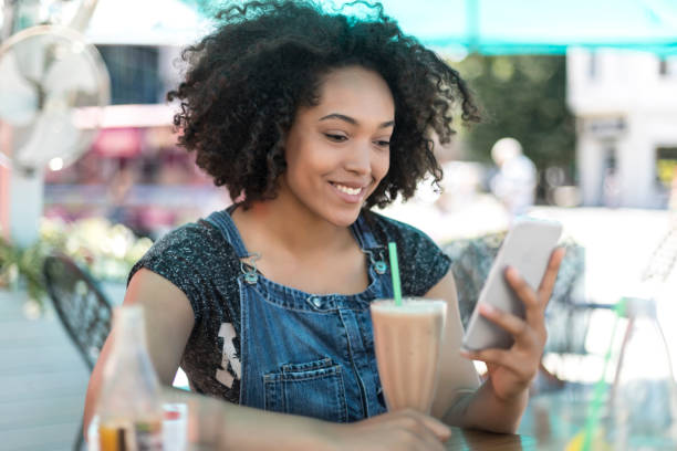 istock Smiling african woman drinking cocktail in cafeteria 884586518