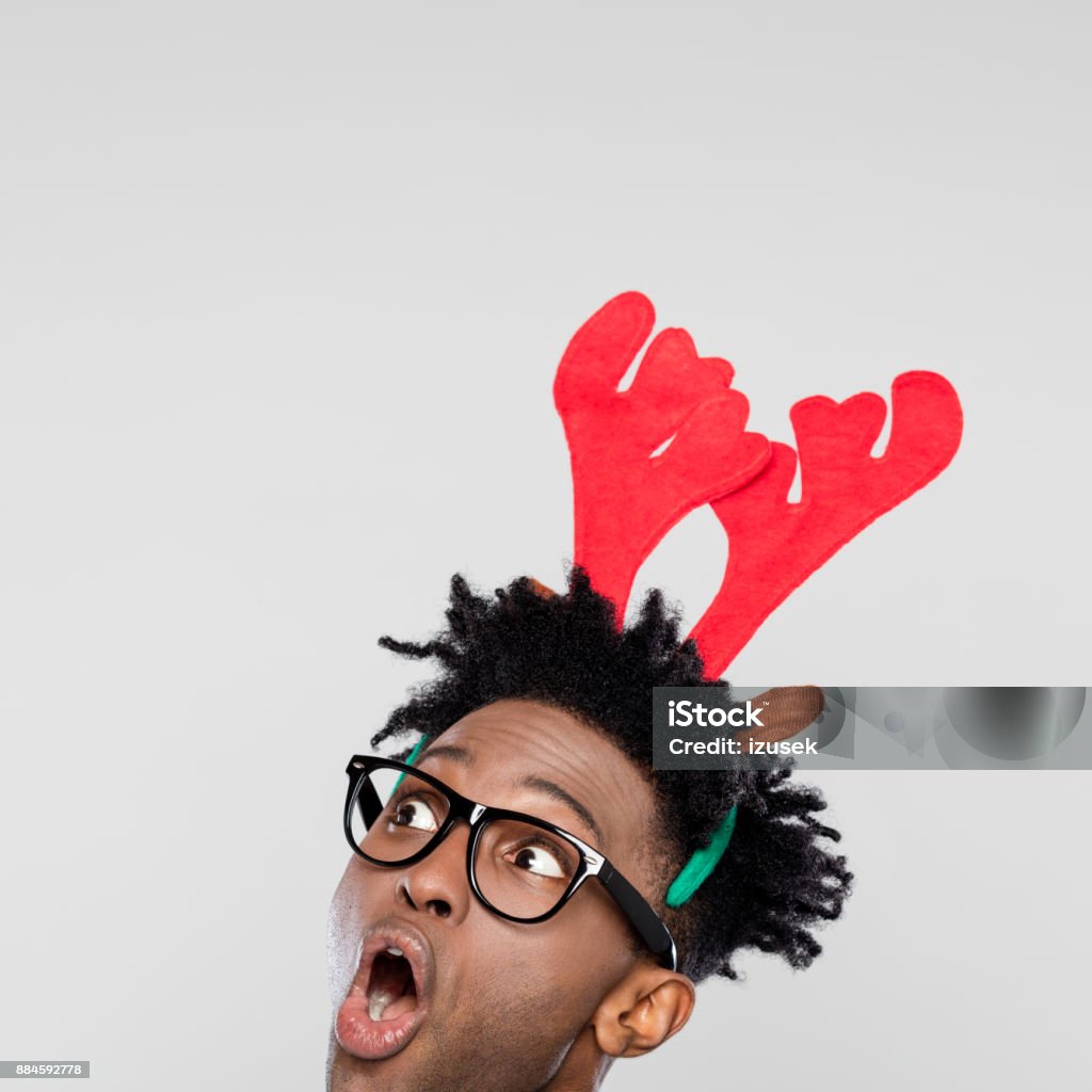 Christmas portrait of surprised nerdy man wearing reindeer handband hores Funny christmas portrait of surprised nerdy young man wearing reindeer handband hores. Close up of face. Rudolph The Red-Nosed Reindeer Stock Photo
