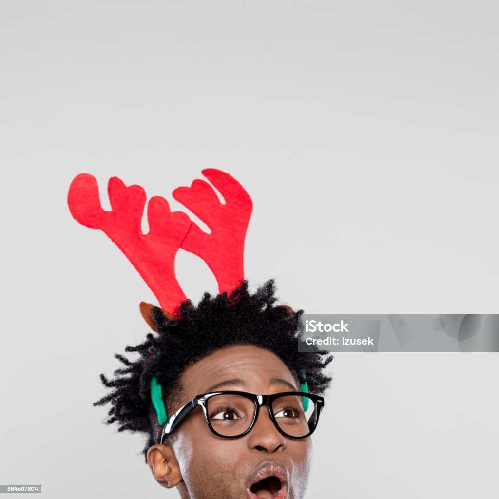Christmas portrait of surprised nerdy man wearing reindeer handband hores Funny christmas portrait of happy nerdy young man wearing reindeer handband hores. Close up of face. Christmas Stock Photo