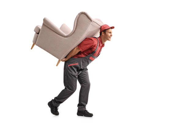 istock Mover walking and carrying an armchair on his back 884619422