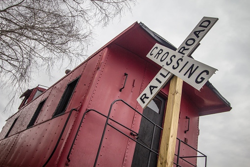 Railroad Crossing Sign With Vintage Red Caboose In The Rural American Midwest