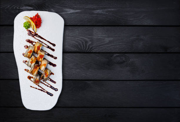 istock Sushi Roll with eel and salmon caviar. Top view. Black wooden background. 884629758