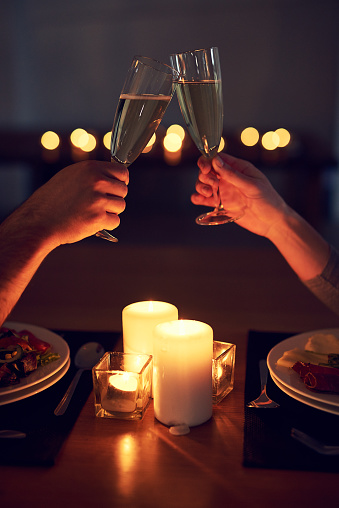 Cropped shot of an unrecognizable couple having a celebratory toast over a candle lit dinner at night