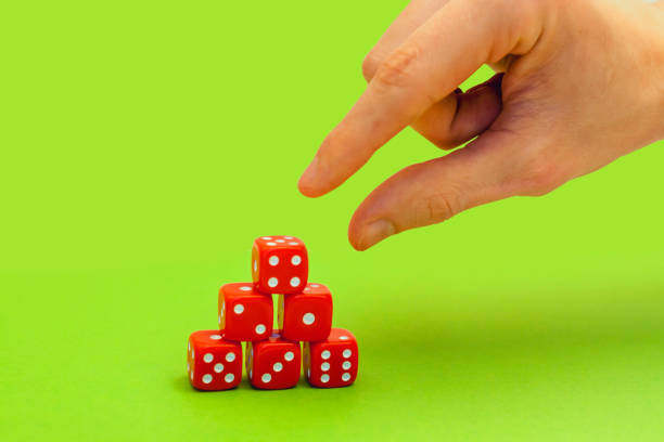 istock hand reaches red dice in a pyramid on green background 884641414
