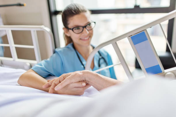 istock Female nurse holding senior woman's hand 884642002