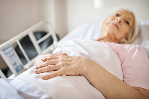 Senior woman lying on hospital bed Senior woman lying on hospital bed. Elderly patient is looking away while resting in ward. She is recovering from illness. sick woman hospital bed stock pictures, royalty-free photos & images