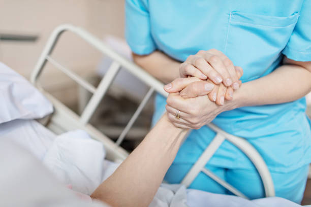 Female nurse holding senior woman's hand Midsection of female nurse holding senior woman's hand. Caring medical professional is with patient. She is consoling elderly woman in hospital. sick woman hospital bed stock pictures, royalty-free photos & images