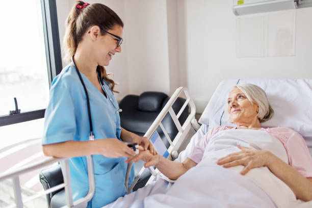 Nurse adjusting oxymeter on senior woman's finger Female nurse adjusting pulse oxymeter on senior woman's finger. Young professional is smiling while looking at patient. Medical worker is examining elderly woman lying on hospital bed. oxygen photos stock pictures, royalty-free photos & images