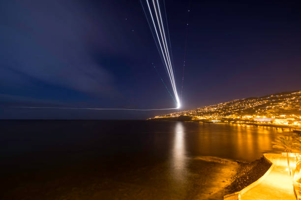istock night city view with airplane light trails 884646618