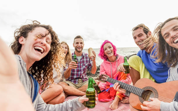 amici adulti takins selfie con fotocamera smartphone alla festa in spiaggia all'aperto - persone felici che si divertono a riprodurre musica e bere birra - concentrati sui ragazzi del centro - tendenze tecnologiche e concetto di amicizia - australia photographing camera beach foto e immagini stock