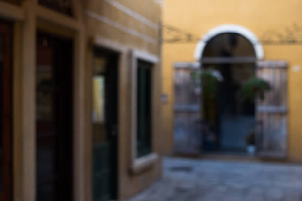 Blur background of yellow wall on Italian style building with wooden doors and stone pathway.
