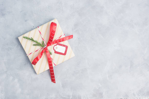 Flat lay top view christma gift withred ribbon an blank tag on grey concrete table