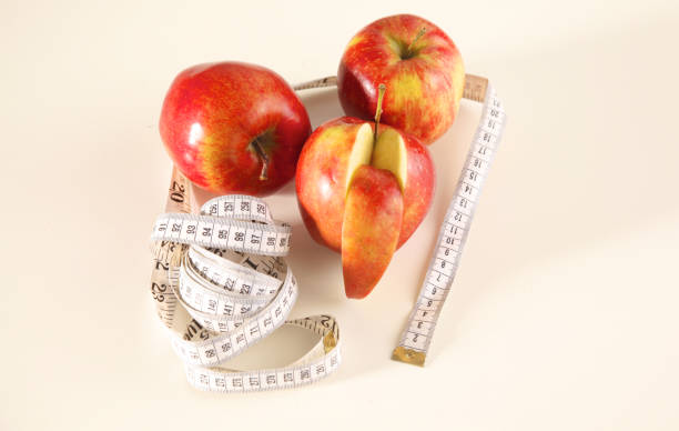 istock apple lying on a table with a stethoscope and measuring tape 884681578