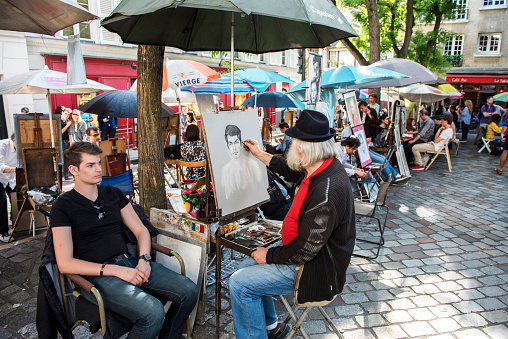 Paris, France - June 7, 2016: Street artist is painting a young boy at Place du Tertre in Montmartre, one of the most touristic attractions of the city