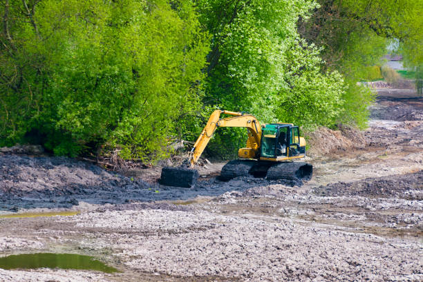 istock Yellow backhoe excavating soil and sand to construct water reservoir 884689340