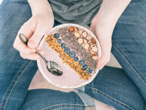 Breakfast bowl in woman hands Eating healthy breakfast bowl. Buckwheat smoothie porrige, fresh berries, seeds and nuts, bee pollen in white ceramic bowl in woman hands. Clean eating, dieting, detox, vegetarian food concept eating chia seeds stock pictures, royalty-free photos & images