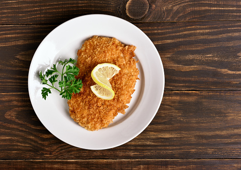 Chicken schnitzel on plate over wooden background, Top view, flat lay