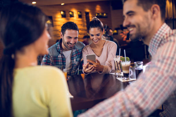 istock Couple using mobile phone during coffee break with friends 884702202