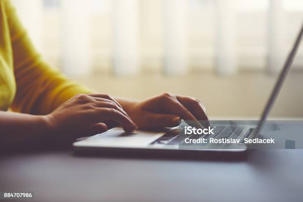 Woman In Office Behind Table Working On Laptop Stock Photo - Download Image Now - Yellow, Close-up, Using Laptop