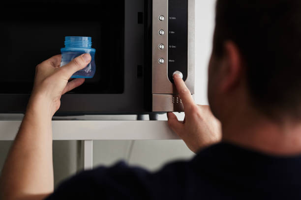 istock Man putting a baby bottle into a microwave 884708588