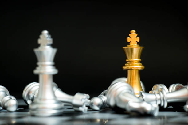 istock Gold king in chess game face with the another silver team on black background (Concept for company strategy, business victory or decision) 884727104