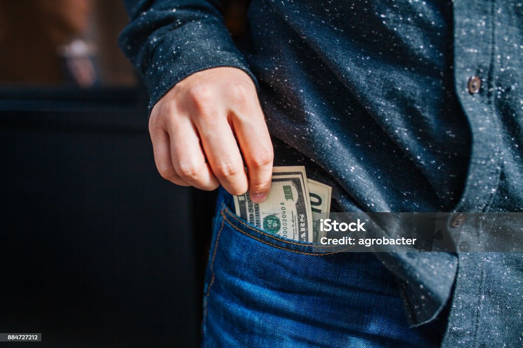 Human hand is putting money in the pocket Pocket Stock Photo
