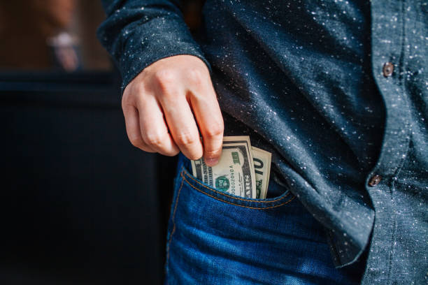 Human hand is putting money in the pocket Human hand is putting money in the pocket hiding place stock pictures, royalty-free photos & images