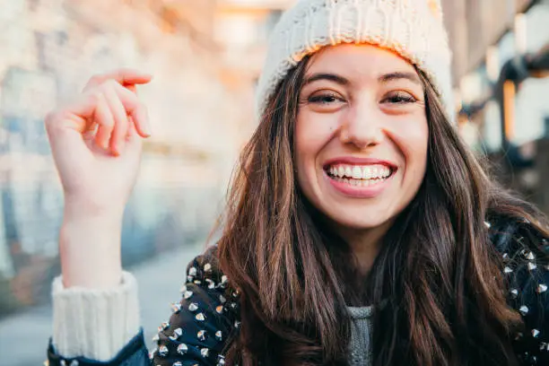 Portrait of a happy and beautiful young woman with woolen cap and lleather jacket laughing