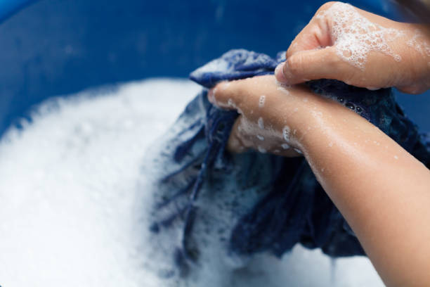 istock Woman hands washing black clothes in blue basin 884732156
