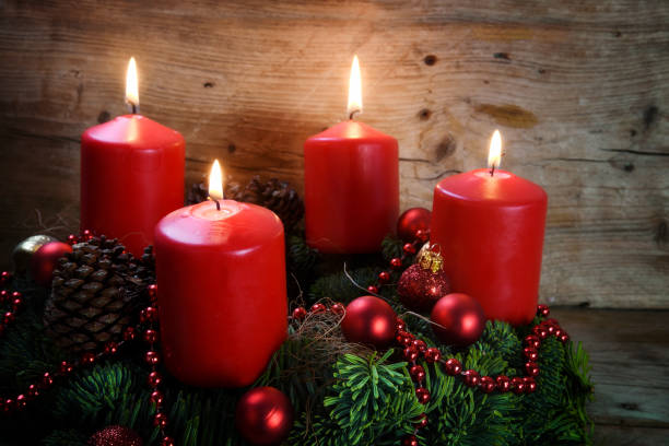 istock Advent wreath from fresh fir tree branches with four red burning candles and christmas decoration on rustic  wood 884732834