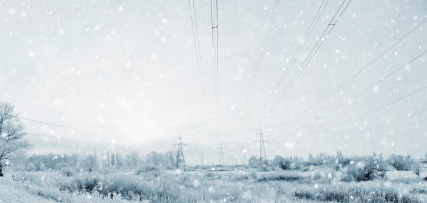 Piloni elettrici nella tempesta d'inverno con una bufera di neve - foto stock