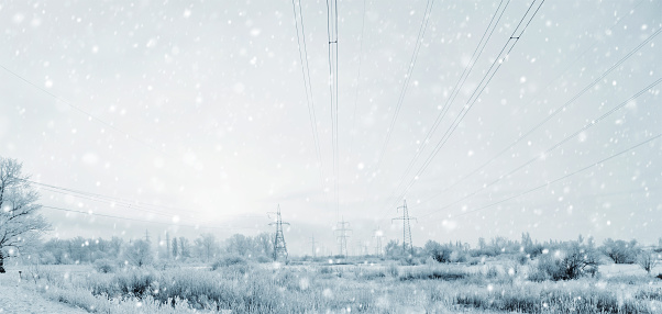 long lines of powerline towers stretching across a Winter Storm with a Blizzard.