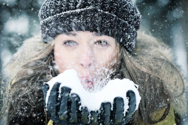 istock Young girl blowing on the snow in his hands 884735656