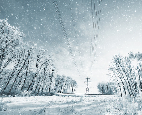 Silhouette of a power pylons  in the Winter Storm with a Blizzard. Duotone.