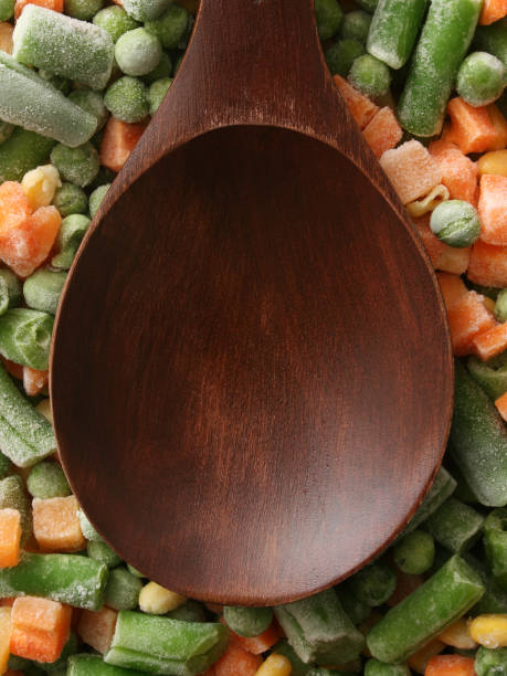 istock Empty wooden spoon over frozen vegetables 884737014