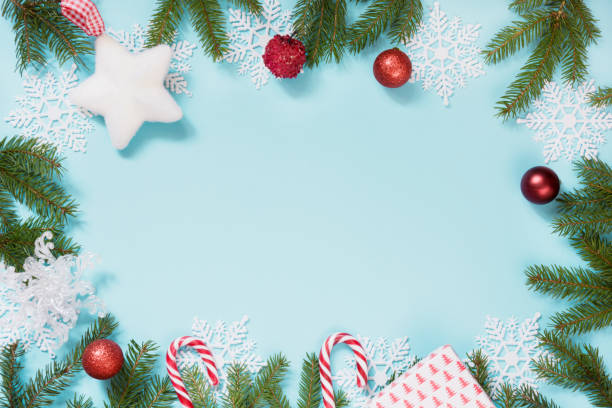 istock Christmas creative border with red balls, snowflakes and branches on blue background. Flat lay. Top view. Copy space. 884737198