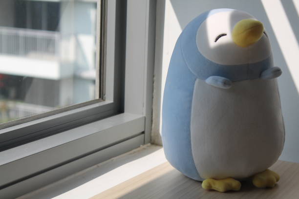 istock Penguin toy sitting by the window in shadows 884737268