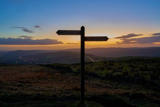 North-south signpost silhoutte. North-south sign on hilltop trail with an orange dusk sky in the background. pennines photos stock pictures, royalty-free photos & images